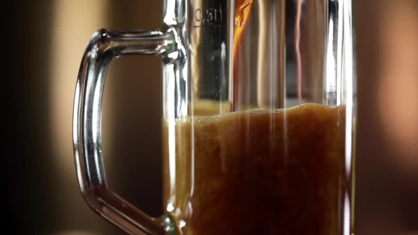 A brown liquid fills a glass mug