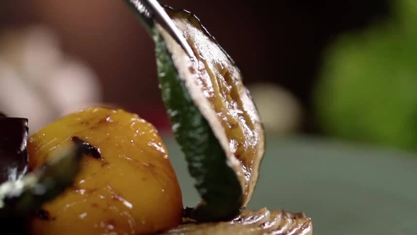 Metal tongs drop a piece of food on a plate