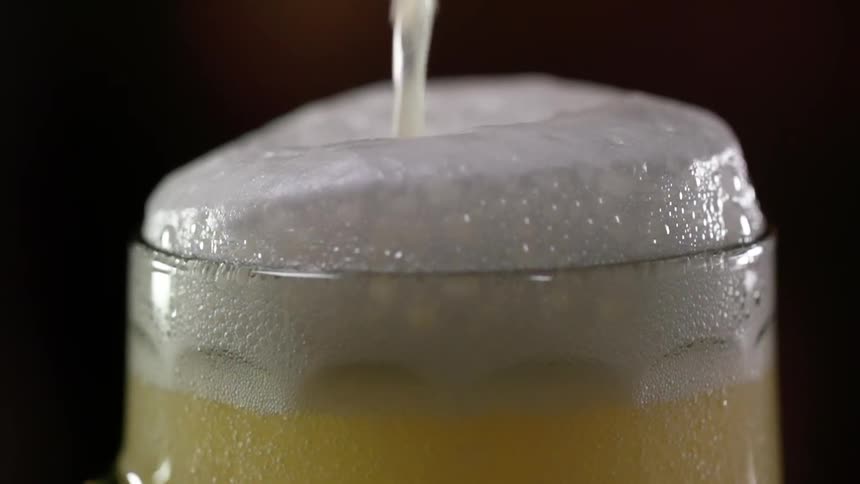 A foamy head rises on a beer mug