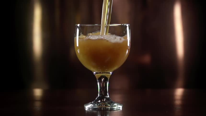 Brown drink is being poured into a glass
