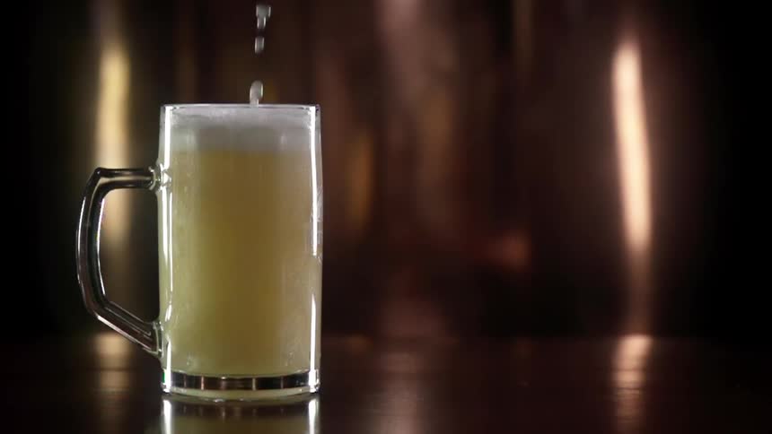 Beer with foam is being poured into a glass