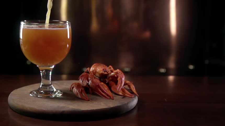 A drink is being poured in to a glass that is sitting next to some seafood in a restaurant