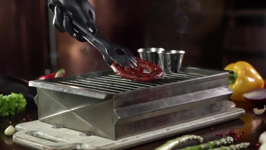 A link sausage is flipped on the grill