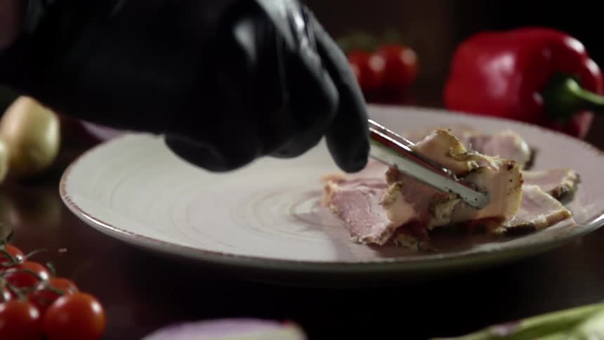Pork belly slices served with tongs on a white porcelain dish