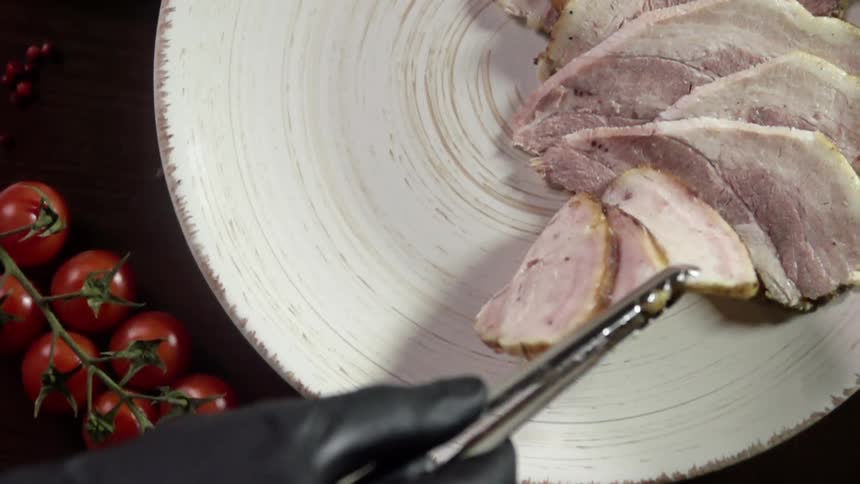 A person puts ham on a plate