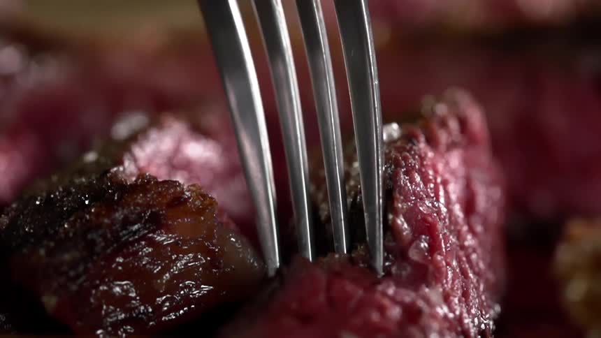A fork is pressed into the rare meat