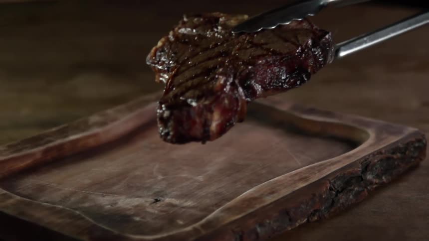 A t bone steak is placed on a wood cutting board