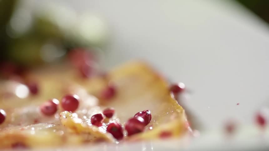 Red grains fall over food in a white ceramic dish