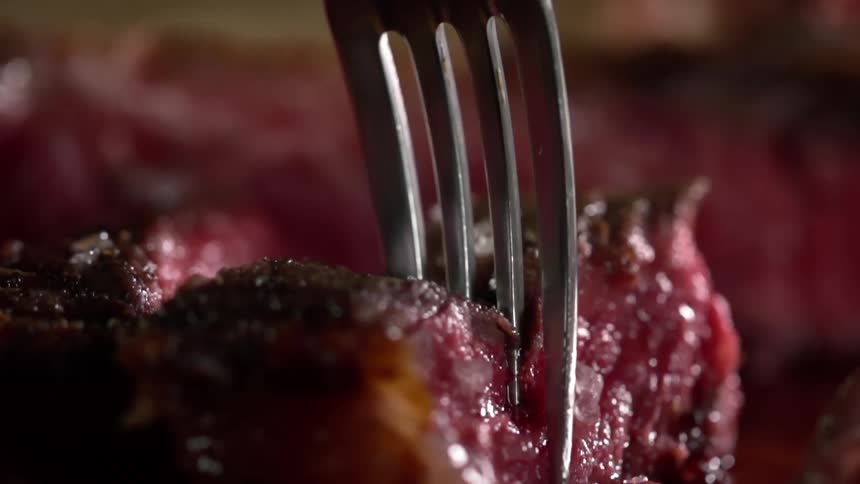 Picking up a piece of rare red meat with a metal fork