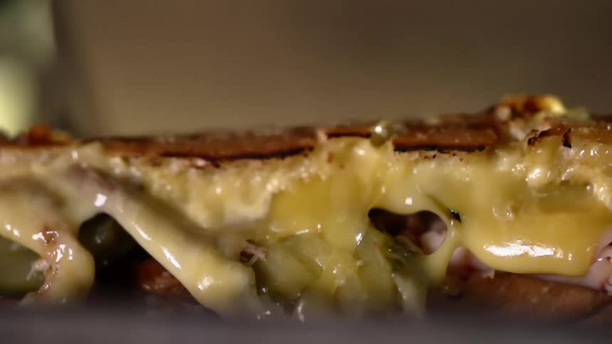 Cheese and sauce oozes out of the side of a sandwich