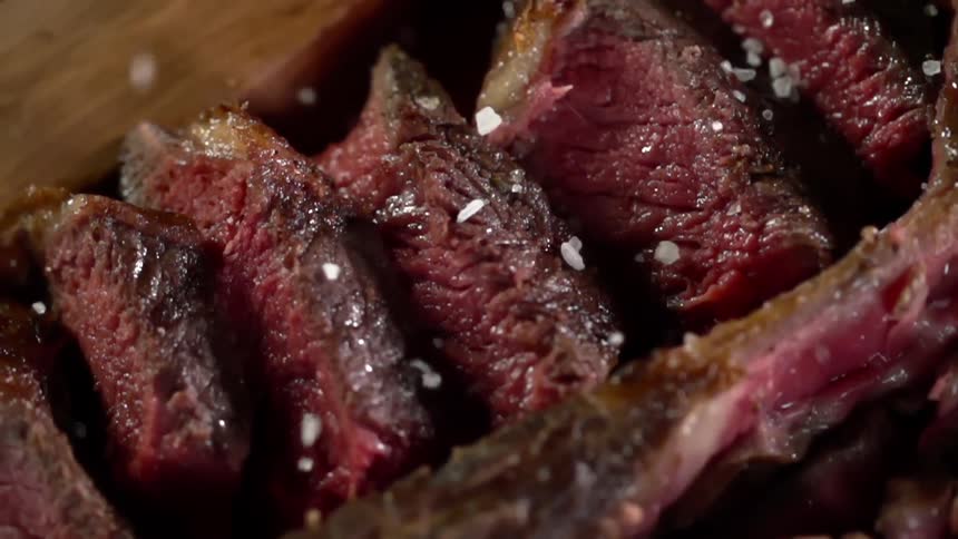 Juicy sliced steak is added salt