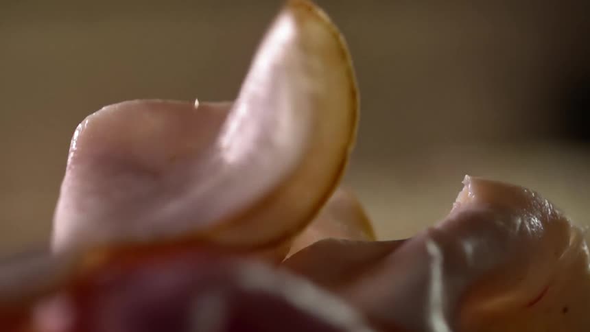 A slice of turkey breast cold cut is dropped down onto others