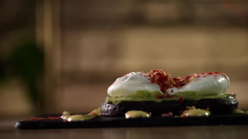 Bacon bits sprinkled over a burger covered in cream and lettuce