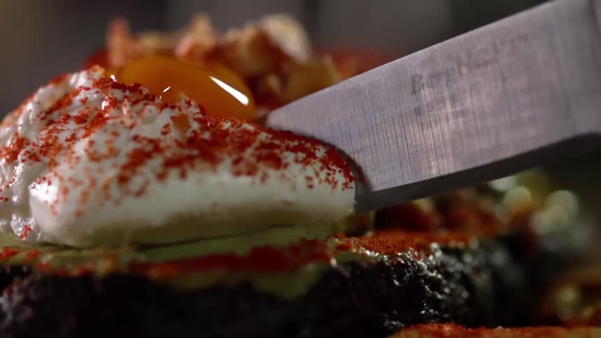 A knife cuts through a frosted dessert
