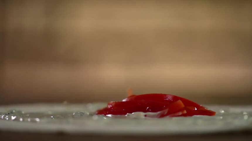 Thin tomato slices fall on a plate