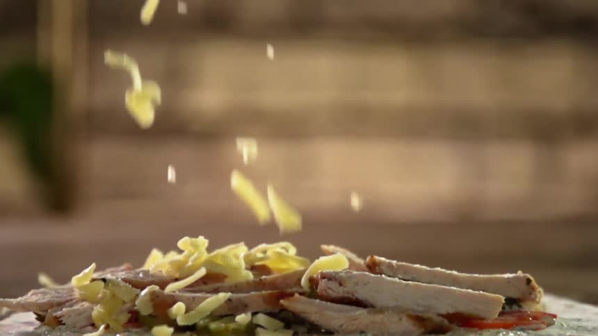 Shredded cheese drops over meat slices