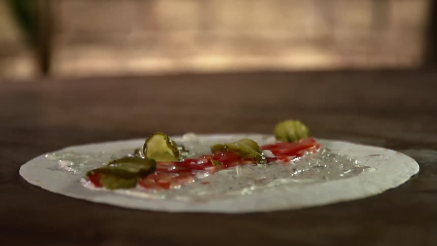 Pickles falling on a wrap with ketchup and sauce