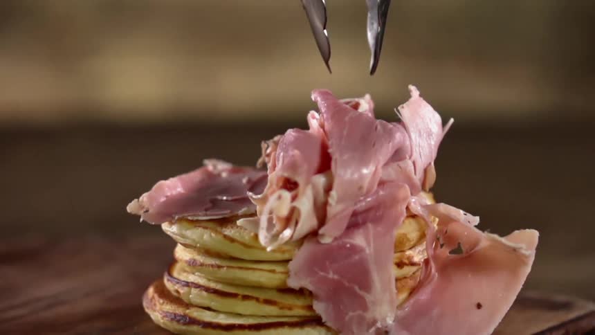 Meat is dropped on to a pile of pancakes