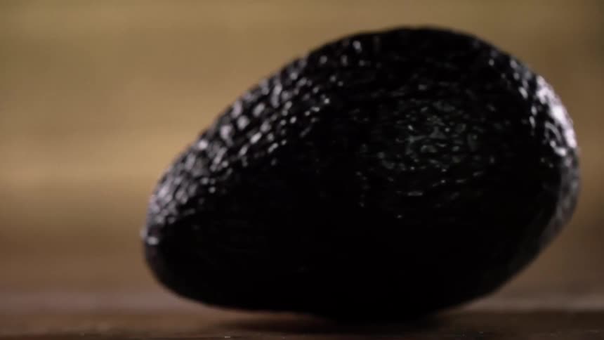 A tropical dark green avocado turns around on the countertop