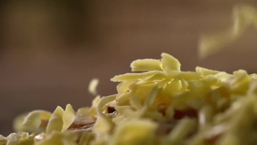Shredded cheese falling on to a pizza crust