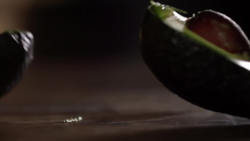 A sliced avocado splits in half as its dropped on a counter