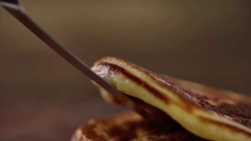A pancake is being placed with a spatula