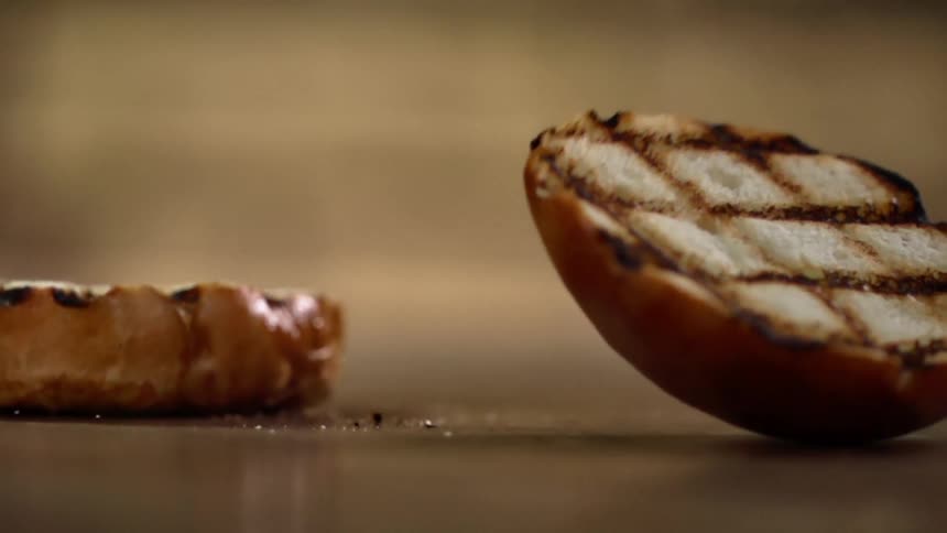 Grilled hamburger bun sliced in half falls on a surfaces bouncing