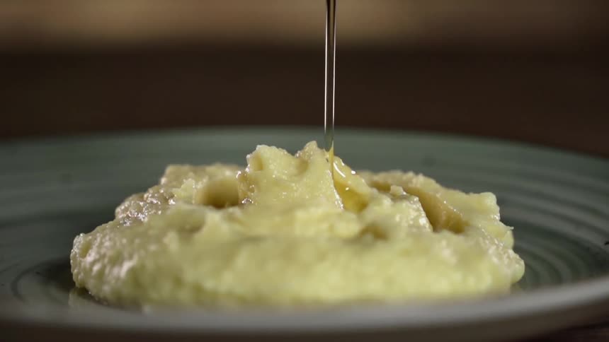 Golden melted butter is poured onto a plated serving of mashed potato