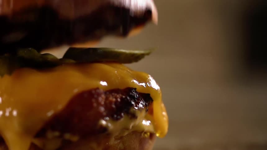 A cheeseburger is topped off with a toasted bun
