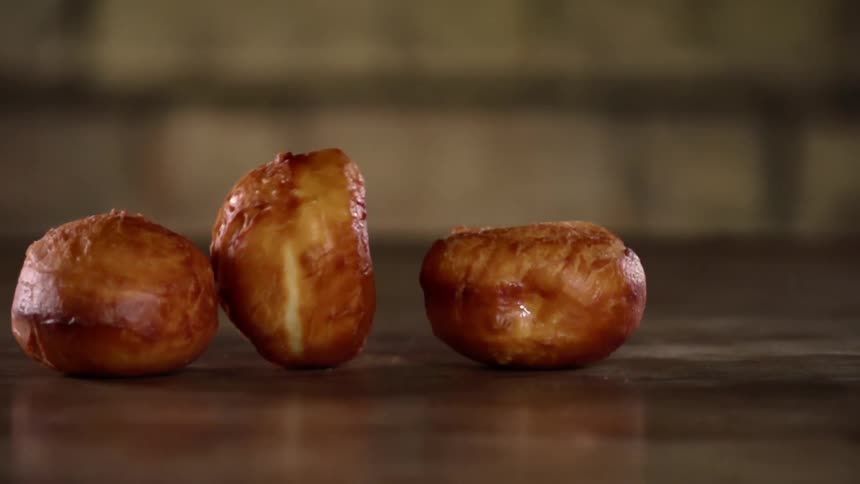 Three bread rolls drop and roll on a wooden table