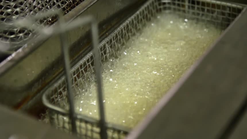 Hot oil bubbles in a basket in a fryer