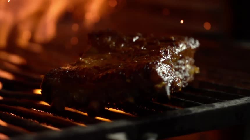 Juicy steak is being cooked with flames on a grill