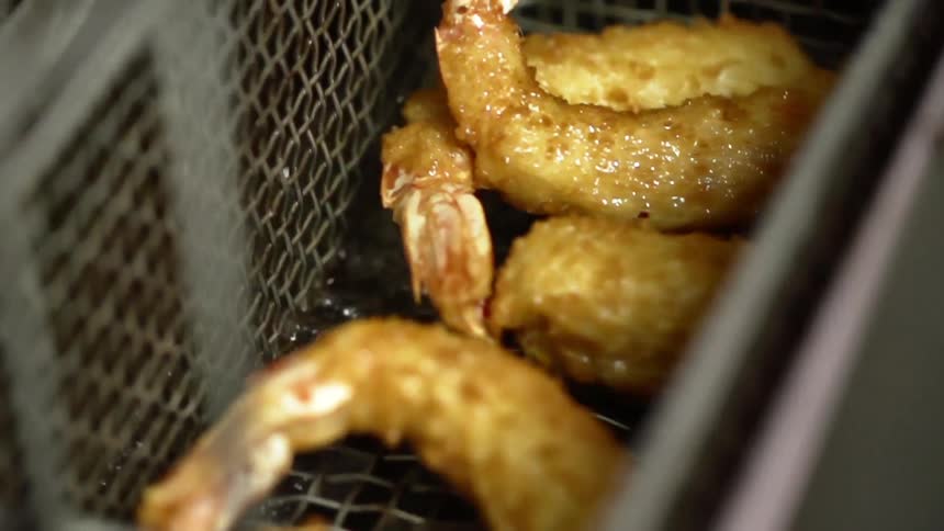 Breaded shrimp is cooked in a deep fryer
