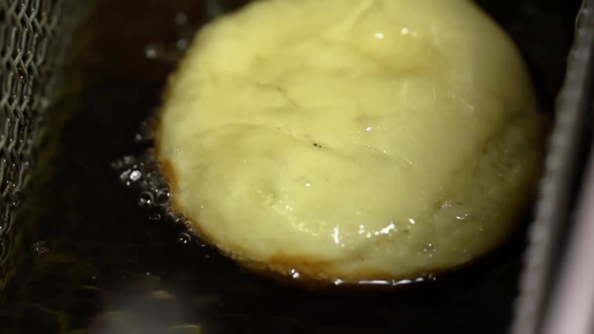 Food cooks in oil in a deep fryer basket