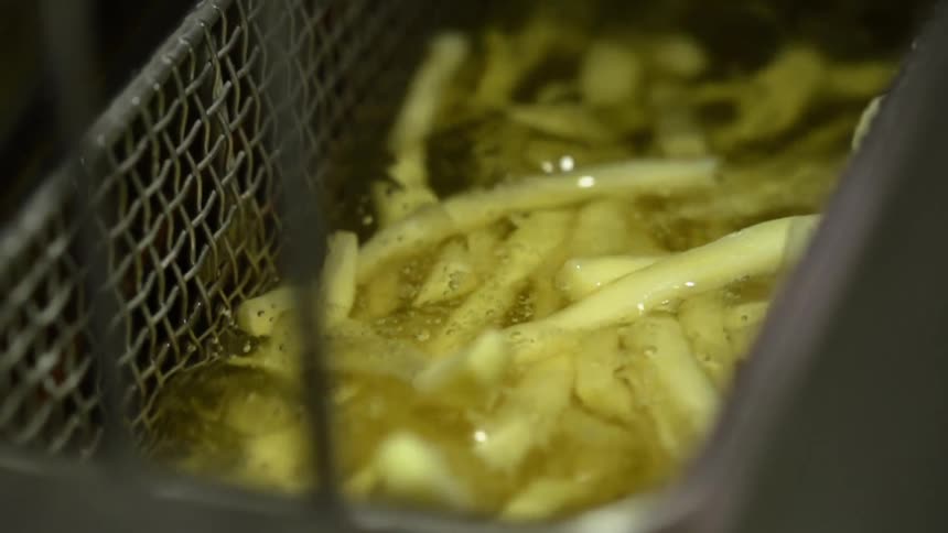 French fries being lowered in to a deep fryer