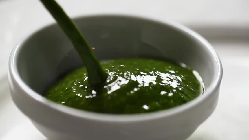 Guacamole is being poured in a small bowl