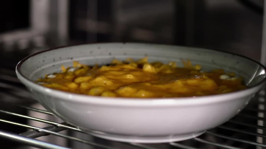 A bowl of soup sits inside a refrigerator