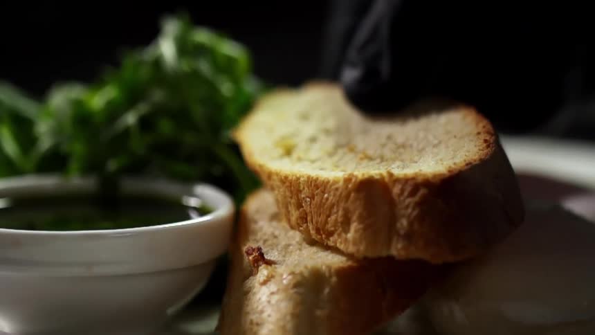 Bread is placed on a plate by a gloved hand