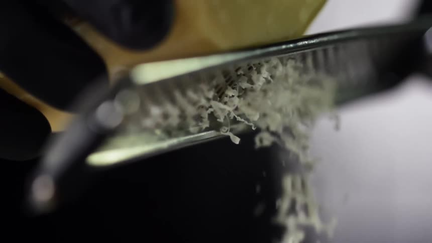 Chef wearing black latex gloves finely grating cheese