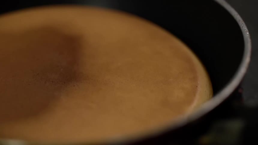 A pancake is flipped in a pan