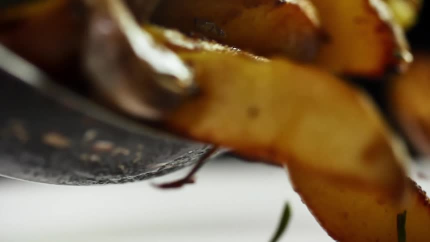 Roasted potato wedges are dropped from a bowl onto the counter