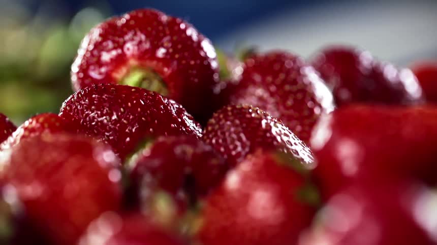 A large pile of fresh and ripe strawberries glisten with moisture