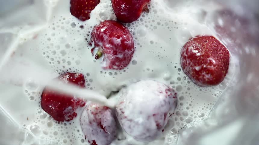 Milk pours over a pile of berries