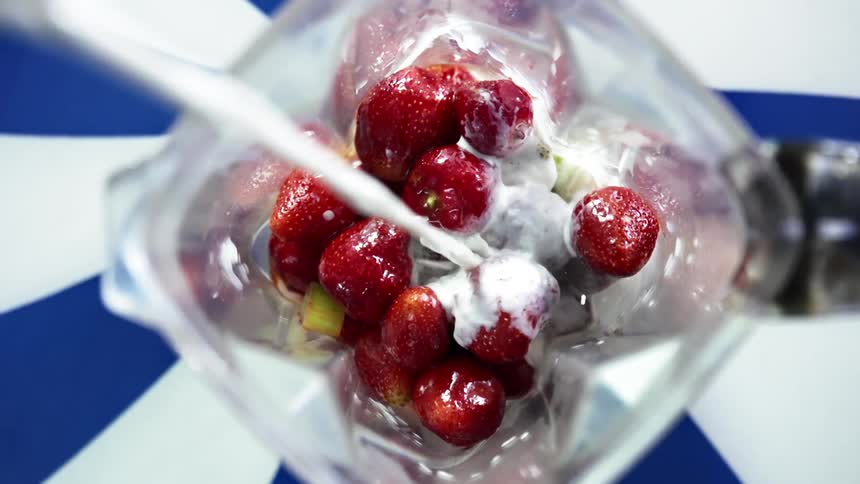 Milk pours into a blender full of fresh fruit