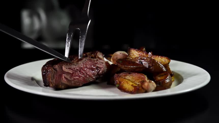 Cooked beef is placed onto a white plate