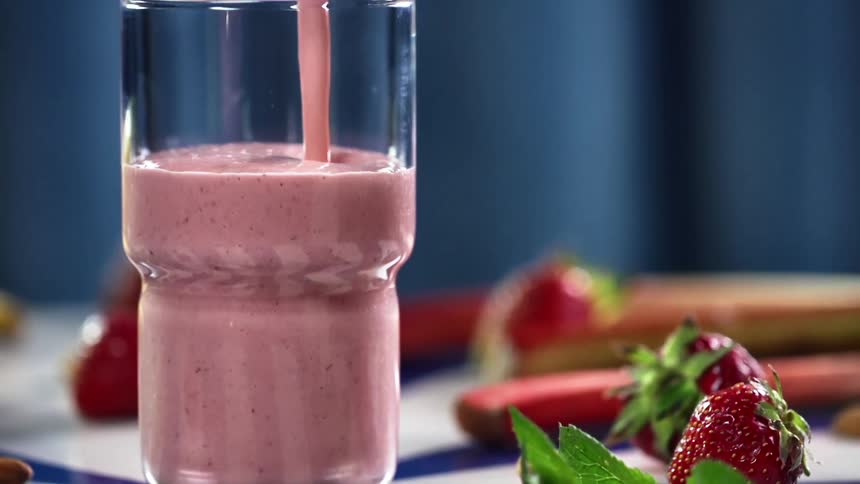 A glass is filled with a fruit smoothie from a pitcher