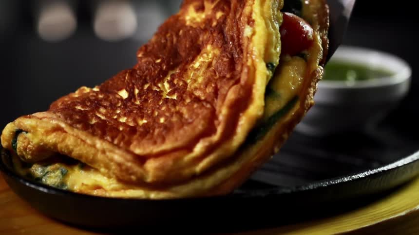 An omelette is set next to sauce on a platter