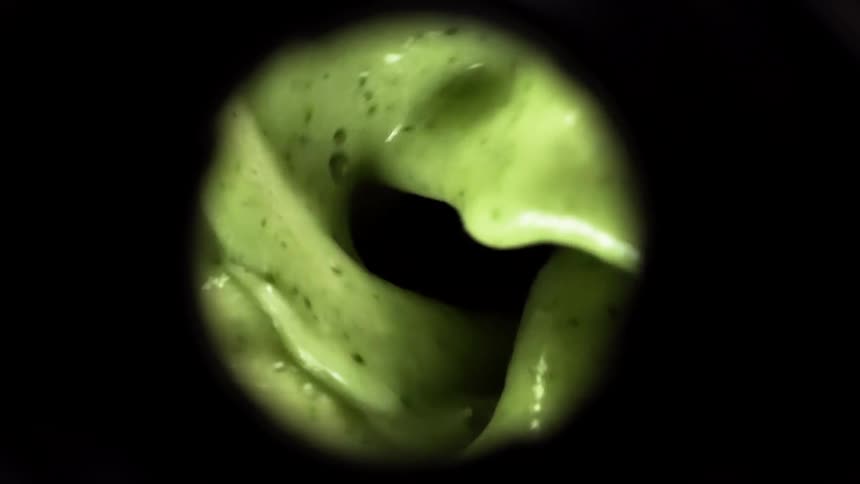 Green liquid is mixed blended and churned causing bubbles