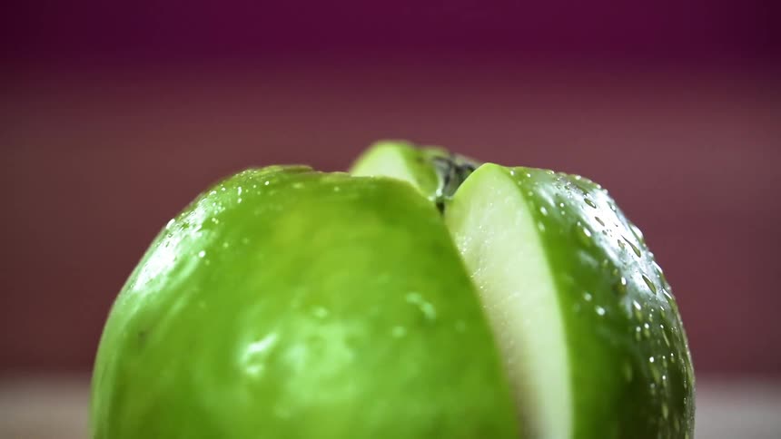 Hand cuts a green apple with a sharp knife