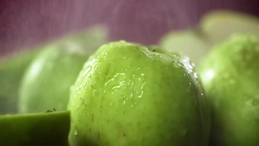 Green apples are being sprayed with water